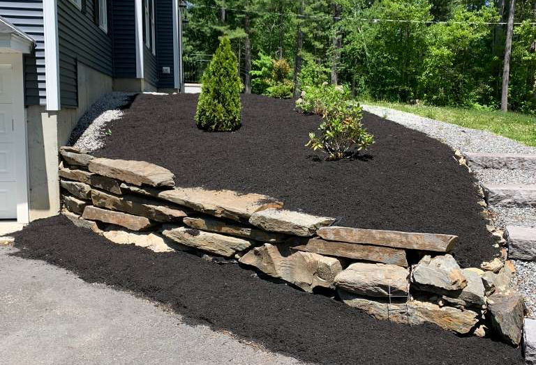 Mulched garden bed with stone retaining wall