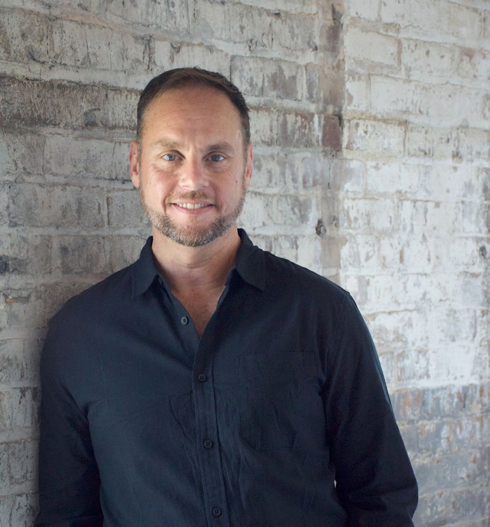 Jamie Watson, founder of The Making Good Studio, standing in front of a brick wall
