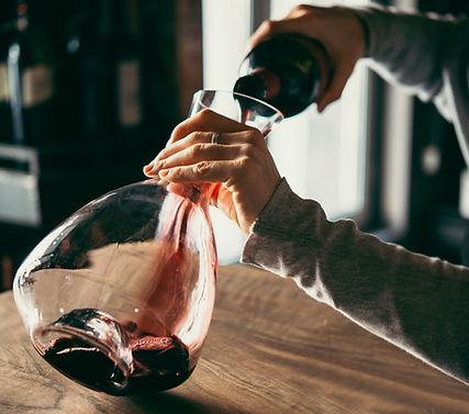 Una persona mentre versa del vino rosso in un decanter di vetro, simbolo di un'esperienza enologica raffinata e attenta alla