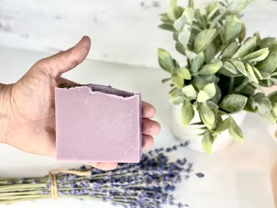 Thumbnail: Hand holding lavender soap with lavender bundle and plant