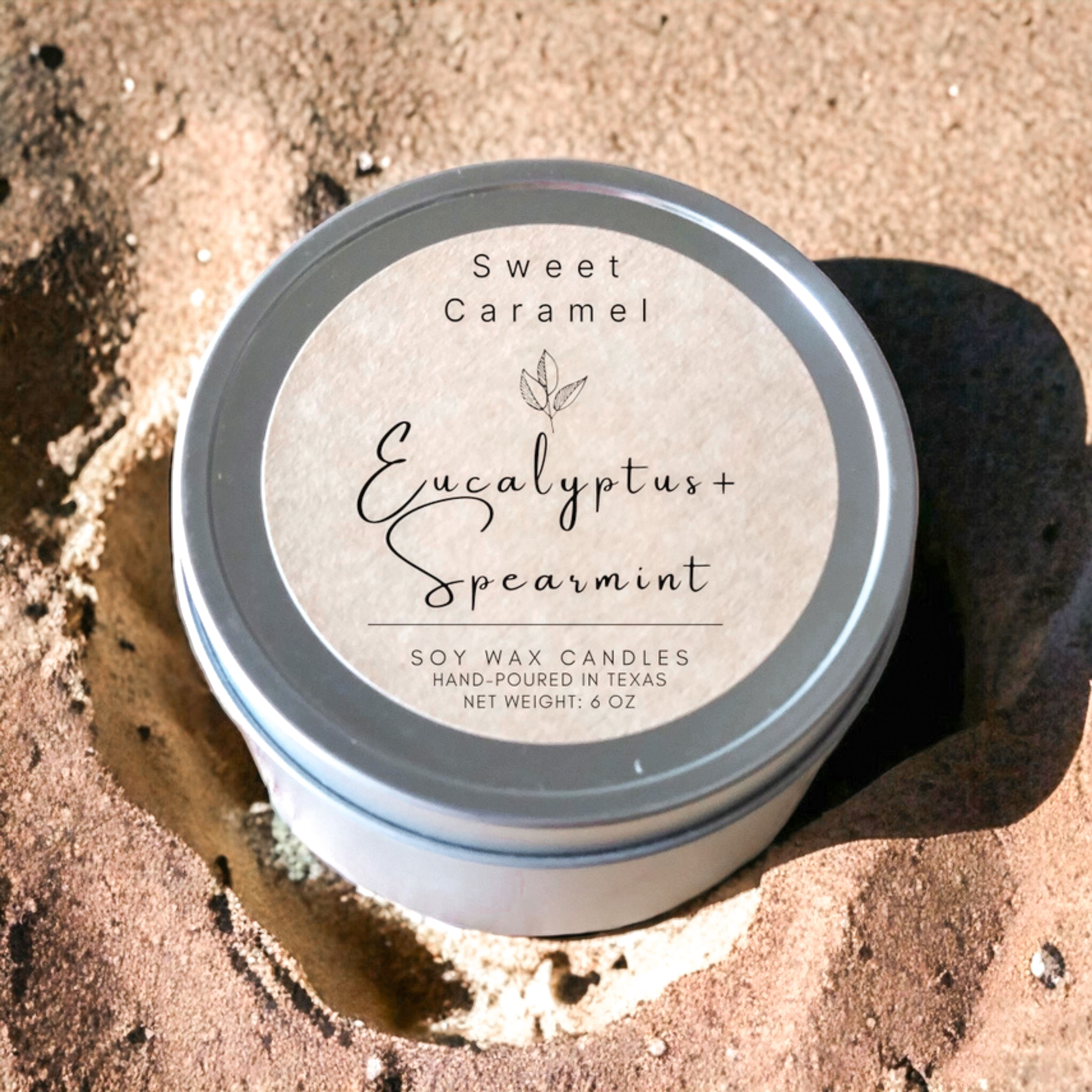 Top view of eucalyptus and spearmint soy candle tin on sand background