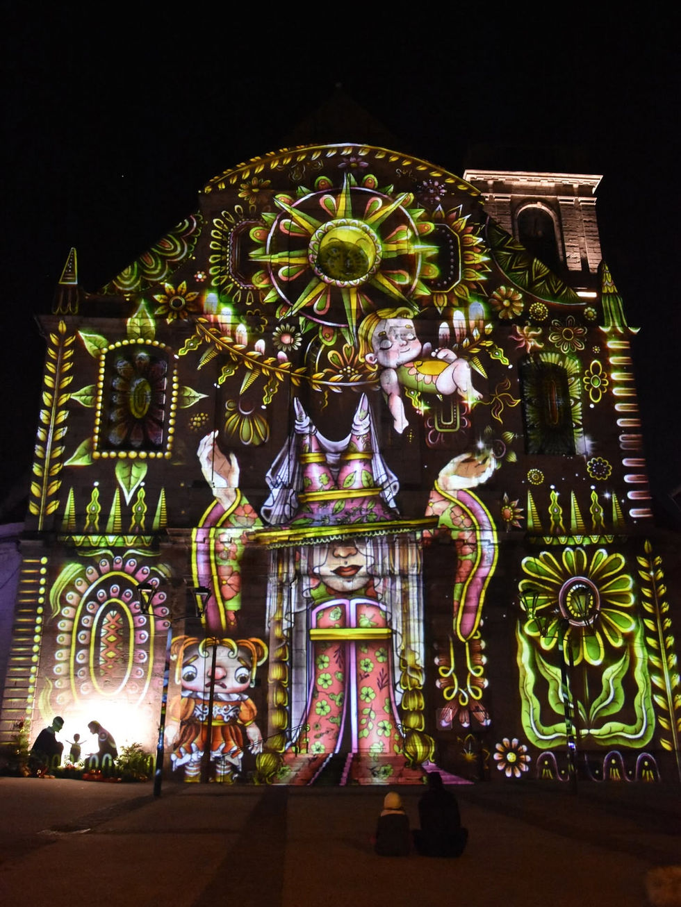 Un visuel élaboré et floral dans des tons jaunes et verts. Une sorcière ou fée semble incanter devant deux enfants endormis paisiblement
Vidéo Mapping Vesoul