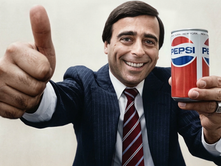 A high-resolution photo-reproduction of the iconic image of Roger Enrico, CEO of Pepsi-Cola USA, from 1985. He is giving a thumbs-up and holding a vintage Pepsi can, with the visual quality enhanced to eliminate aging artifacts from the original photograph.