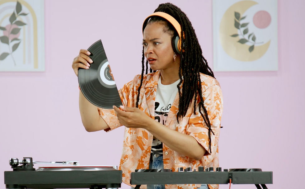 A woman DJ looking at a vinyl record cut in half from a scripted video shoot at Corduroy Media