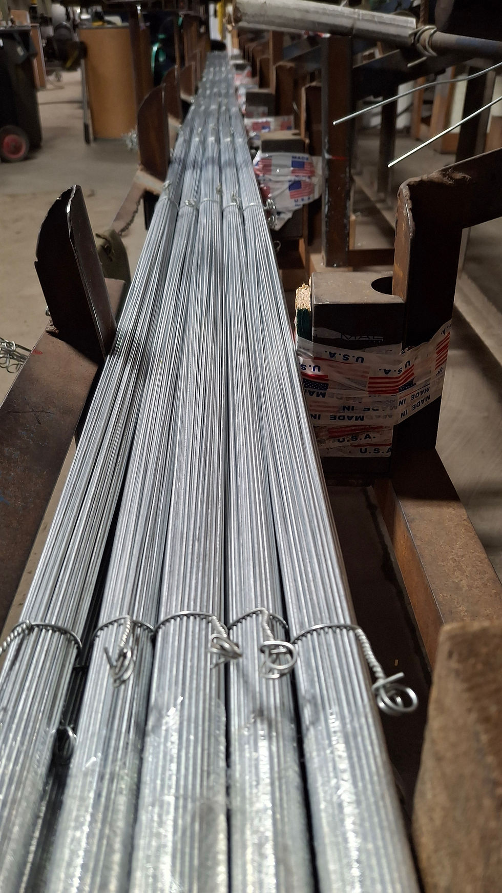 Wire is being cut to specific length in a factory by a straightening and cutting machine. 