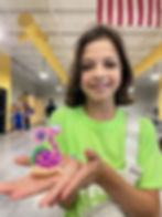 Young girl holding a colorful snail craft smiling in a building hall