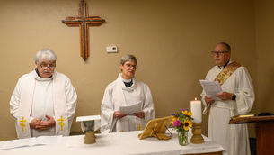 Two priests and a deacon prepare to set the table for eucharist on a Sunday at Emmanuel Harrah.