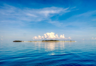 Photo of Twin Island in the Torres Strait - blue sky, blue sea, white clouds and two small islands with beaches