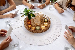 נשים סביב שולחן מקיפות נרות, מחזיקות קלפים, אווירה מוארת, מקום מפגש