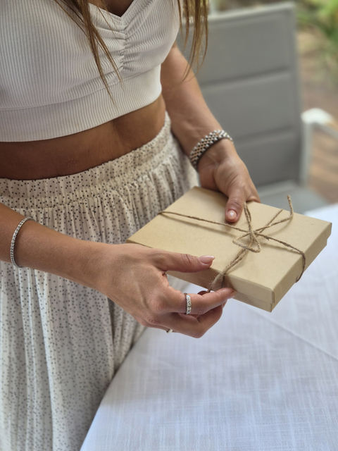 אישה מחזיקה קופסת מתנה חומה קשורה בחוט חום, מצגת מיוחדת