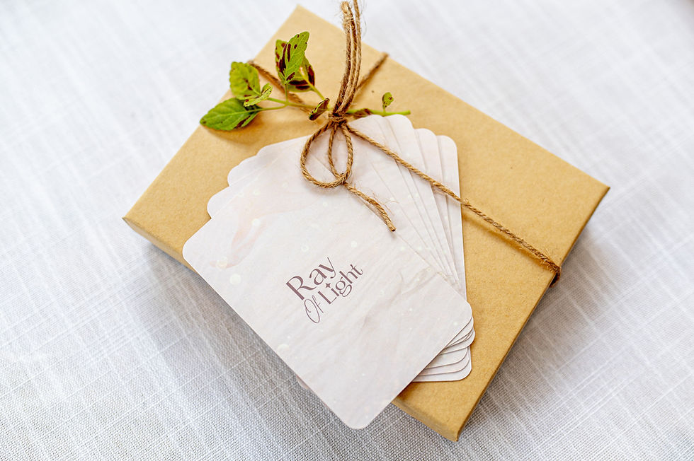 תמונה ממוזערת: קופסת מתנה חומה עם חוט, קלפי Ray of Light, רקע לבן טקסטורלי.