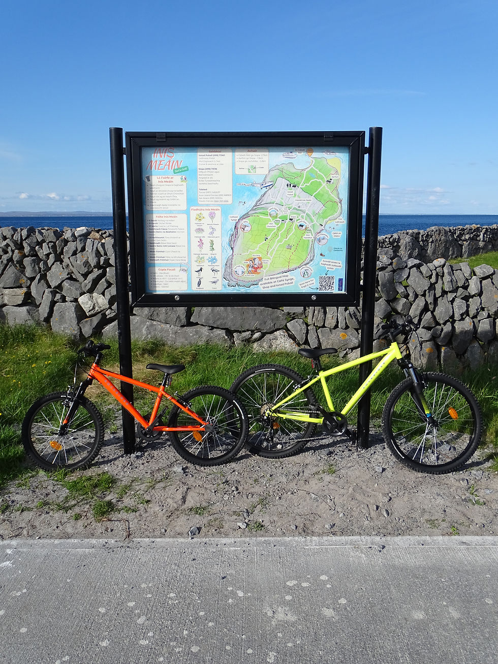Two bicycles parked by a tourist map for bike rentals inis meáin.