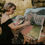Thumbnail: Live painter Cheryl at work, painting on canvas on easel, we see a venue