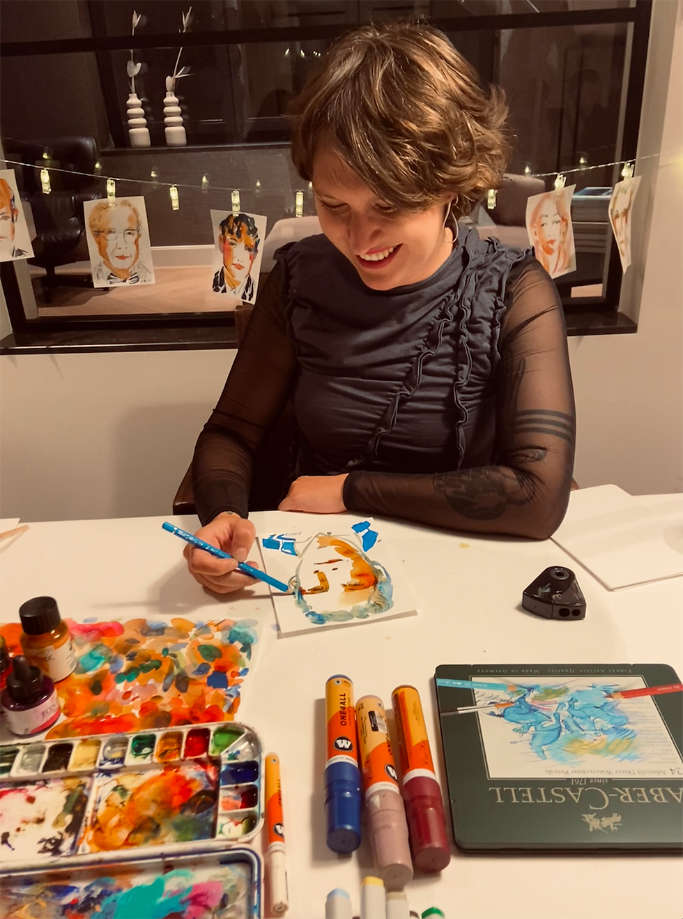 Live illustrator Roxy profile photo of her sketching on table with paints