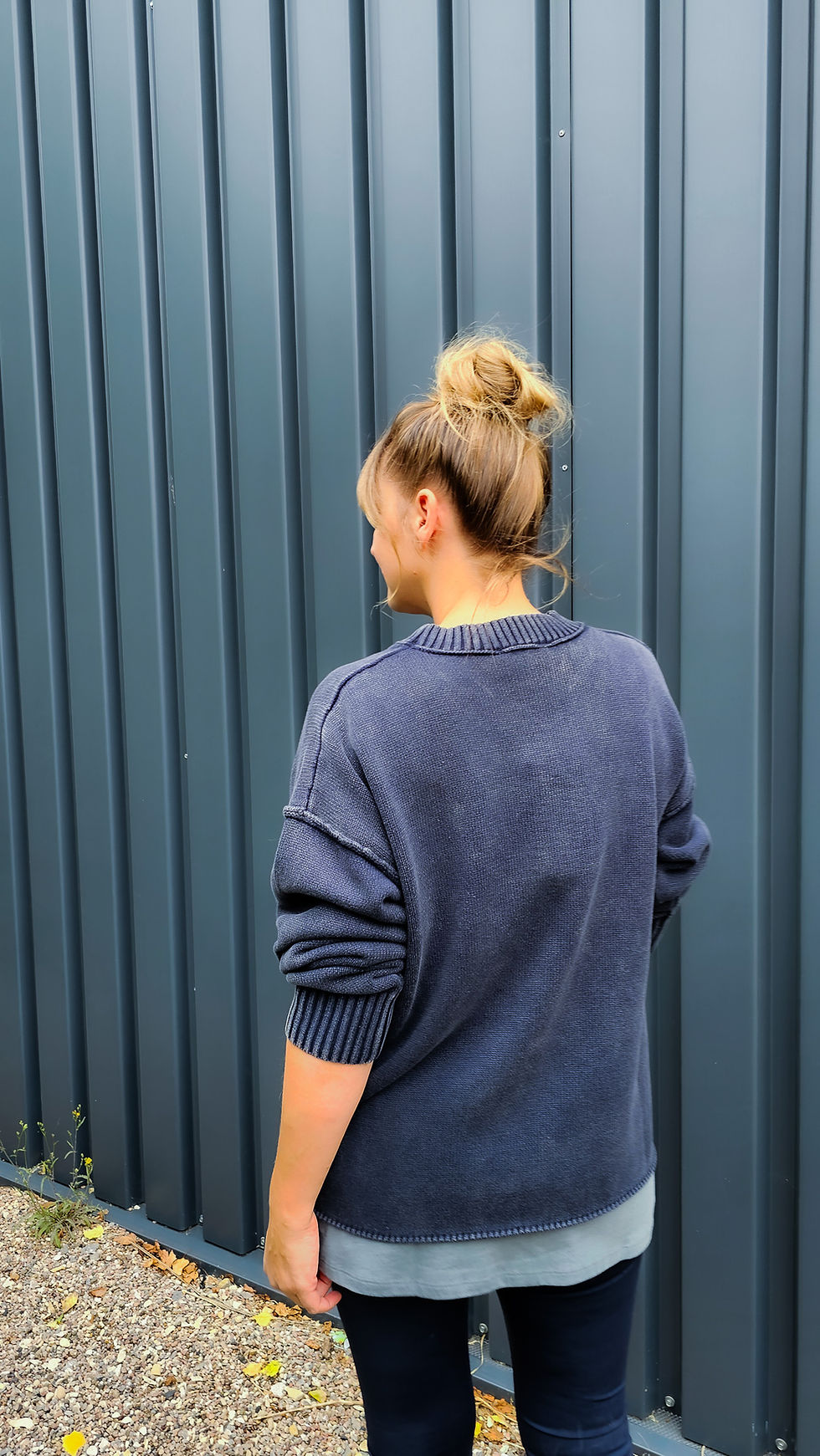 Miniaturbild: Model trägt gewaschenen Baumwollpullover in After Midnight Wash mit Ziernaht und langem Top in grau darunter. Rückenseite