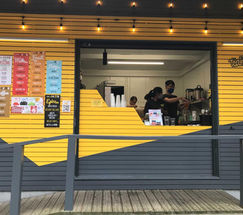 images of a permanent pop-up stall fit-out, featuring a ramp for accessibility, a secure lockable and retractable window, and a bespoke counter, all designed and fitted in the brand’s yellow and red colours by SB Carpentry & Building