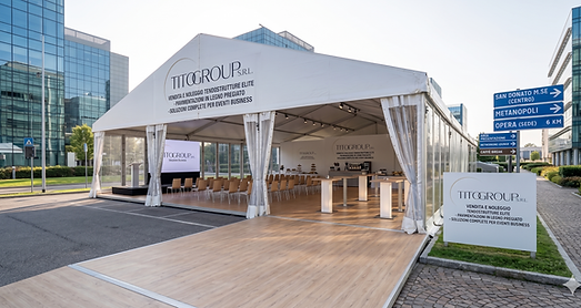 llestimento business Tito Group S.r.l. a San Donato Milanese (Metanopoli): tendostruttura Bifalda bianca per eventi aziendali con pavimentazione tecnica in legno chiaro originale. L'interno è configurato per networking con tavoli alti e display LED. Il cartello esterno mostra il logo ufficiale Tito Group con indicazioni stradali per San Donato Centro e la sede di Opera a 6 km.