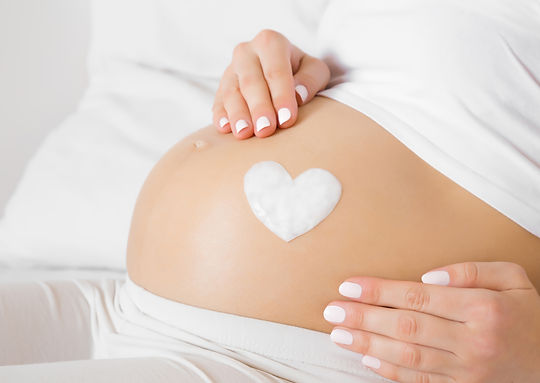 Pregnant Belly with heart lotion on it.