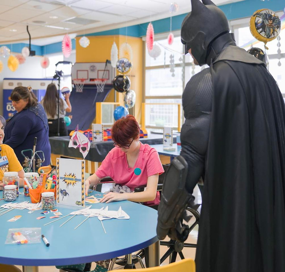 Batman overlooking nurse helping children color in hospital