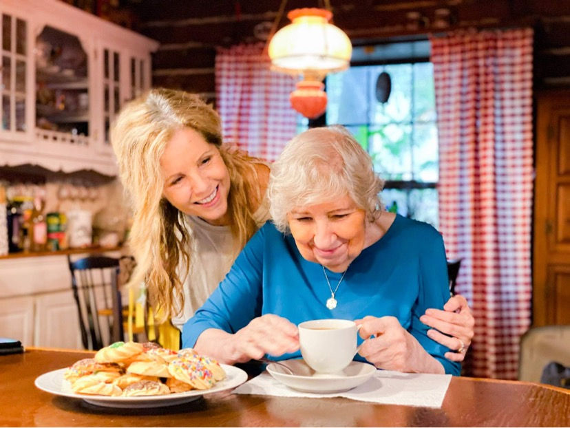 Tina K hugging her mom sitting at a table