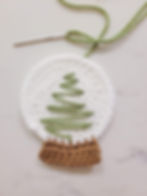 A tapestry needle and green yarn used to stitch on the tree