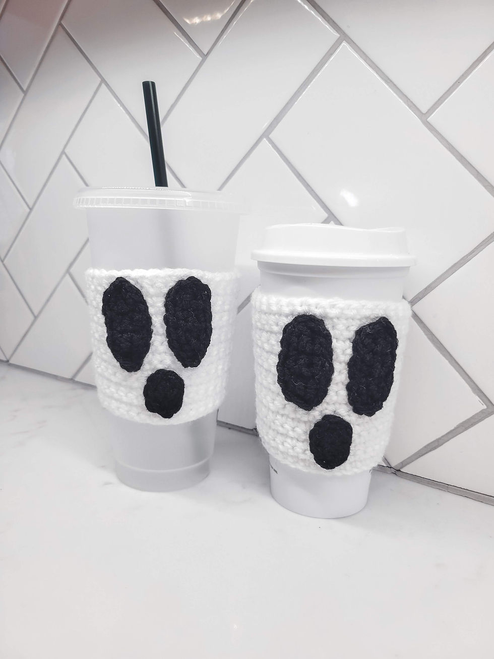 The crochet ghost cozy displayed on a venti and grande size mug.