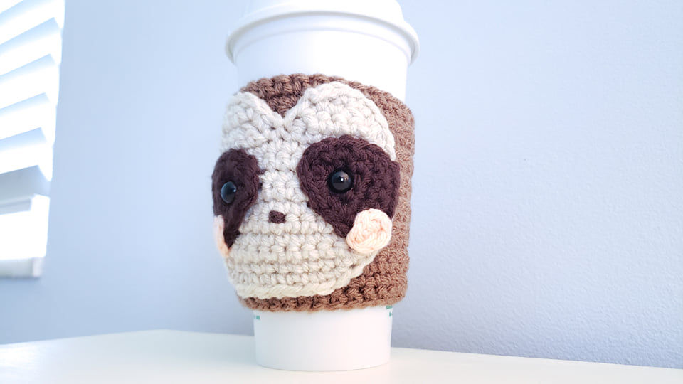 The crochet sloth cozy displayed on a reusable Starbucks mug.