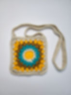 A yellow, blue, caramel and cream starburst granny square bag laying on a white background.