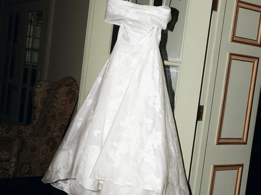 Strapless white wedding dress hanging on a door