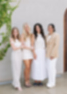 Four wedding coordinators smiling in white outfits outside