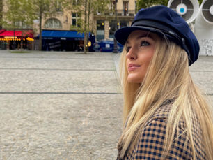 Young woman staring off in the streets of Paris with a long coat and a navy hat