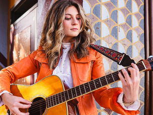 Young woman holding a guitar looking down and playing it