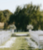 Outdoor wedding aisle with white chairs and floral decor