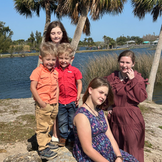 Five kids sitting and standing on a rock.