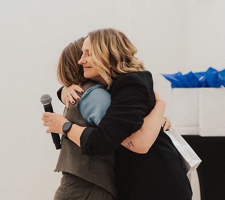 Dvi moterys apsikabina po apdovanojimo ceremonijos