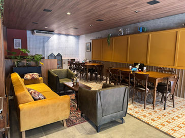 Interior de café acolhedor com sofás, poltronas e mesas de madeira.