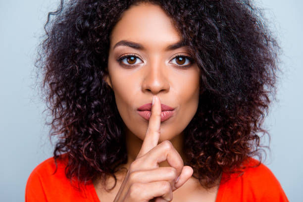A woman with her finger over her lips in silence