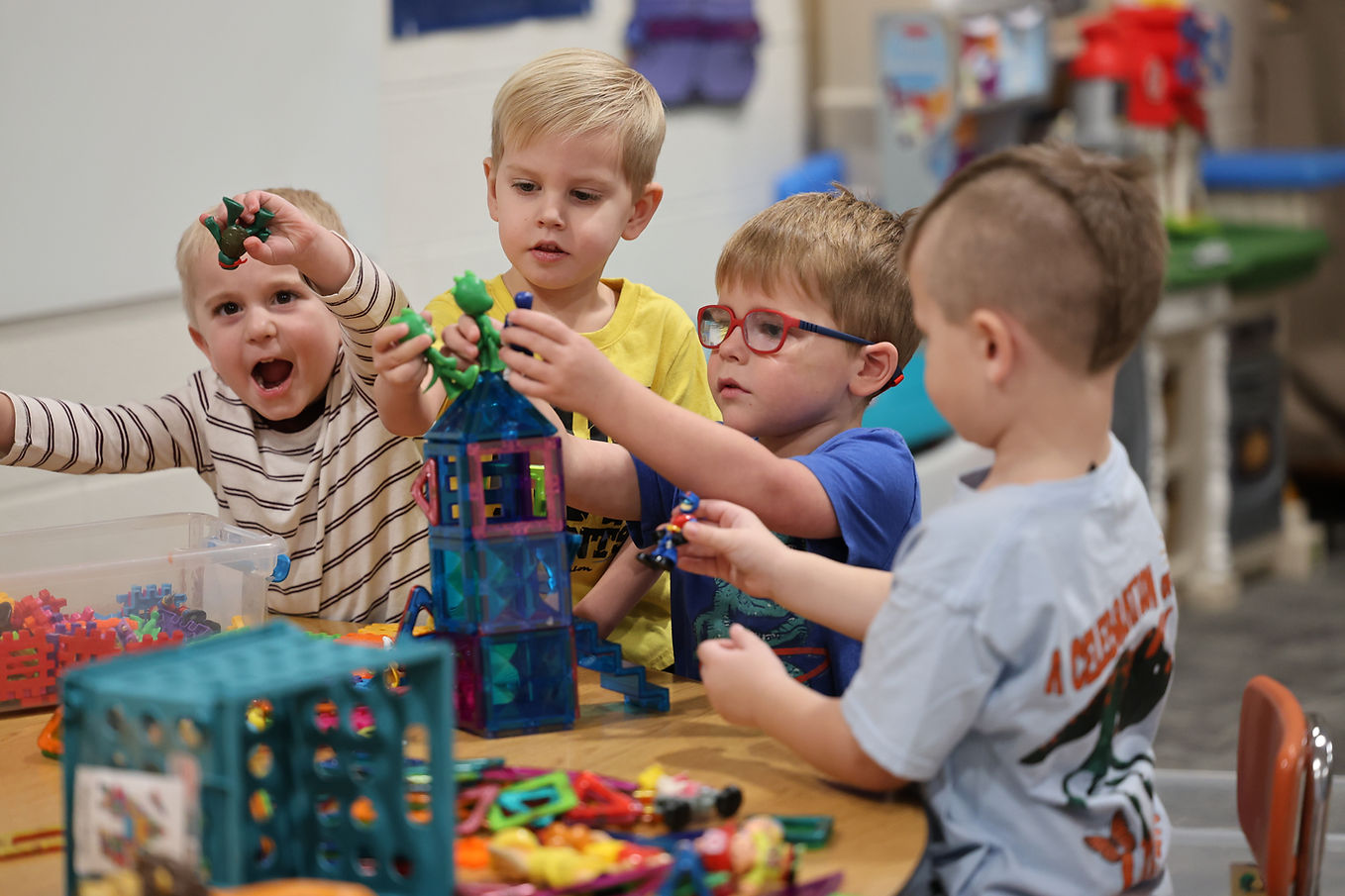 Four young children playing with magnetic building blocks.