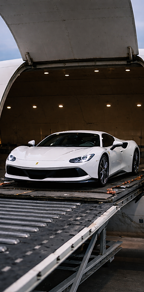 A white Ferrari sports car is positioned inside the open cargo hold of an airplane, transport read.
