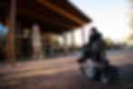Person in front of a museum sitting in a wheelchair outfitted with a Free Form Back