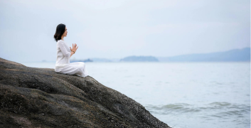 Person sitting peacefully by the ocean reflecting on mental wellness