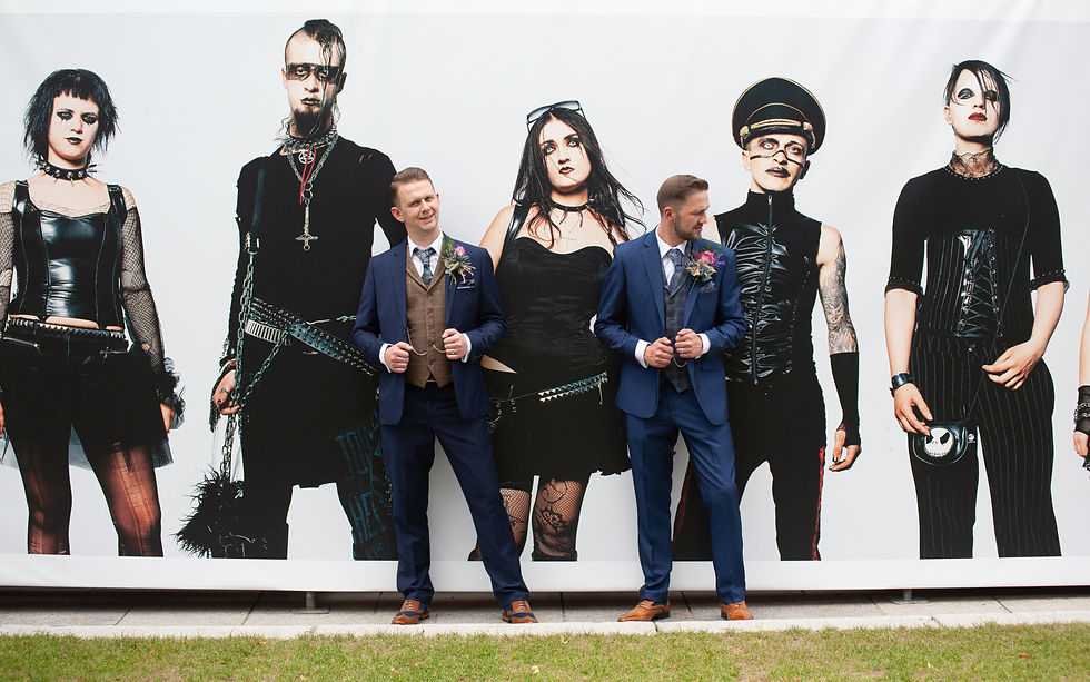 Two guys posing infront of a rock band mural