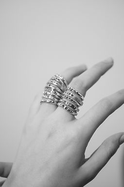 Hand adorned with numerous stacked silver rings.