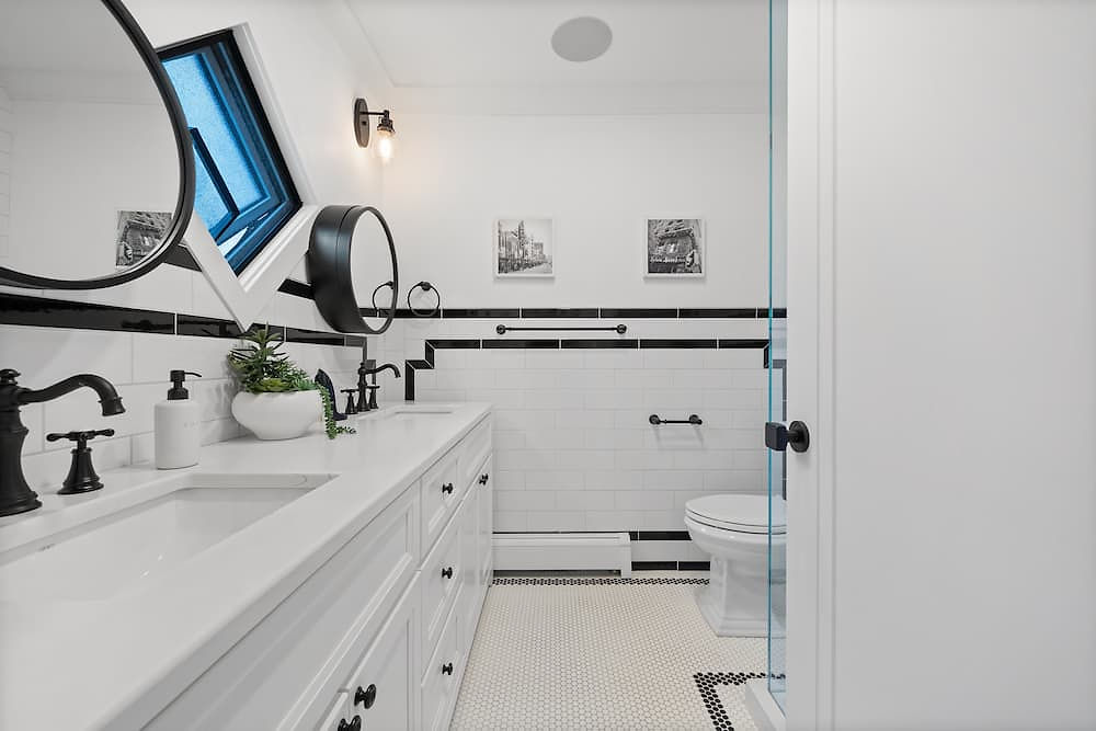 a bathroom sink with black and white decorative subway tile and black fixtures