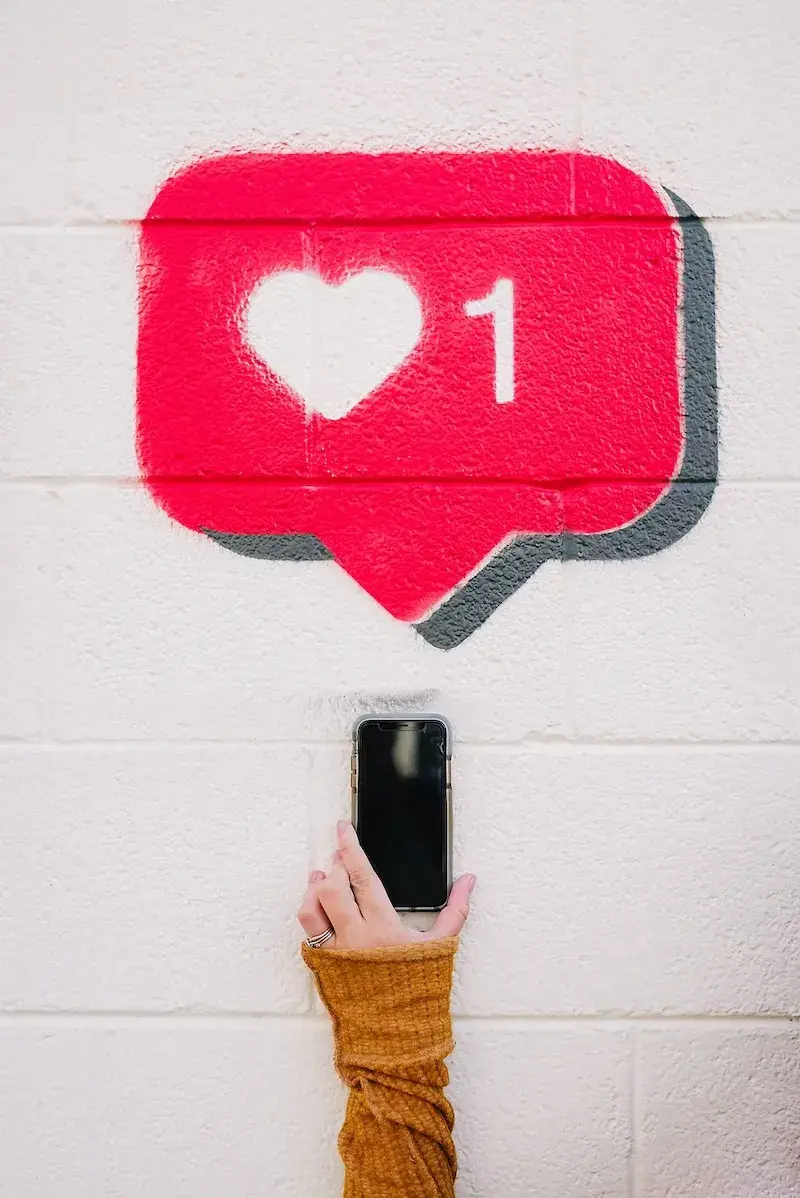 person holding up phone with heart notification above