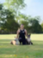 Rachel Perry with two dogs in a green sunny field