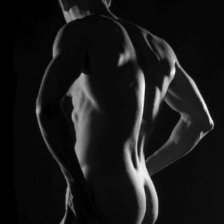 Nu artistique masculin de dos en noir et blanc, éclairage dramatique soulignant les muscles du dos.