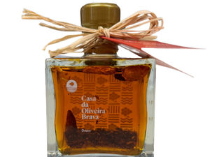 A stout, square glass bottle with an amber-colored liquid that's piri piri infused olive oil.