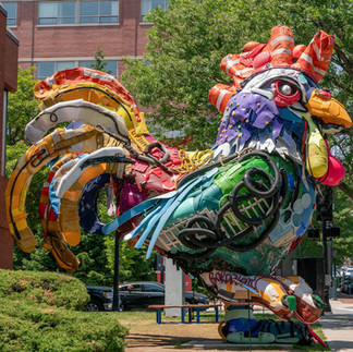 Large statue on a streetfront of a rooster created entirely from plastic trash by bordallo ii