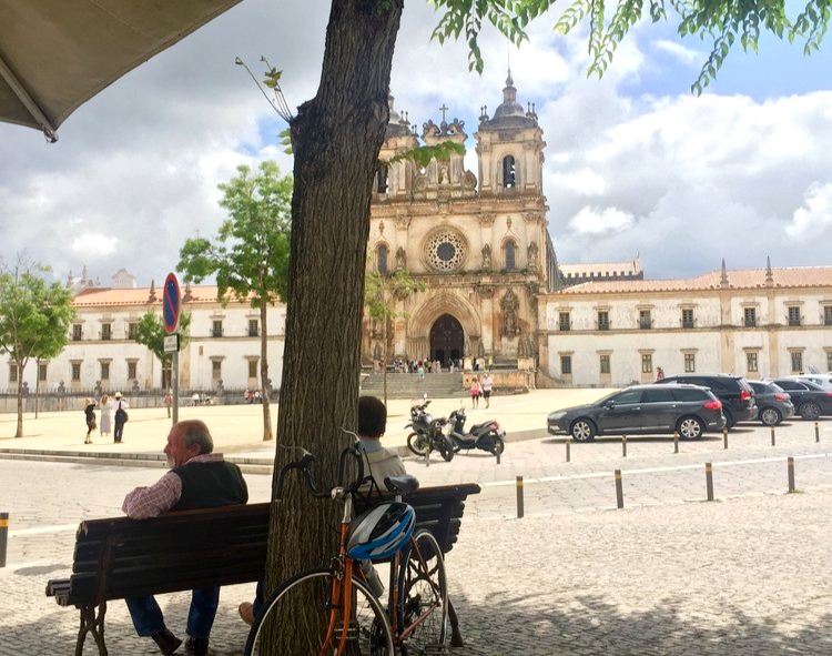 A couple sits on a bench in front of the monastery in Alcobaca, Portugal